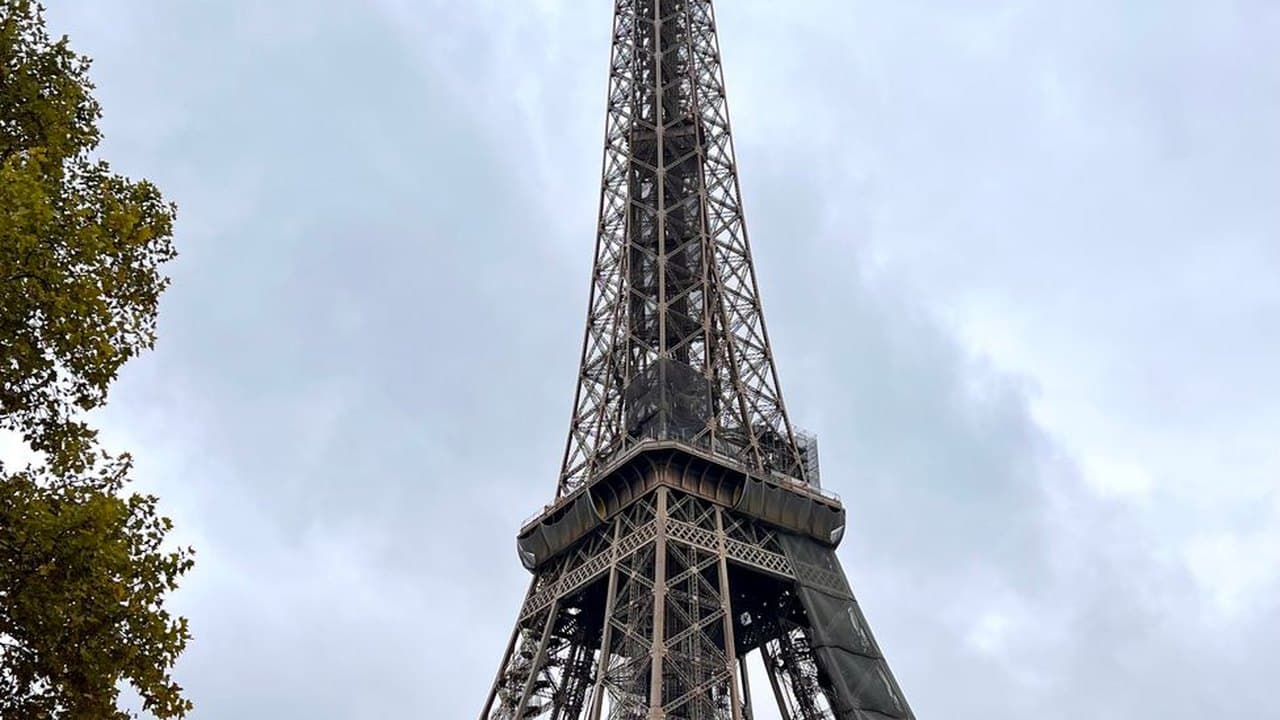The Eiffel Tower seen from below against a cloudy Paris sky, a structure a group of artists publicly protested before it was finished