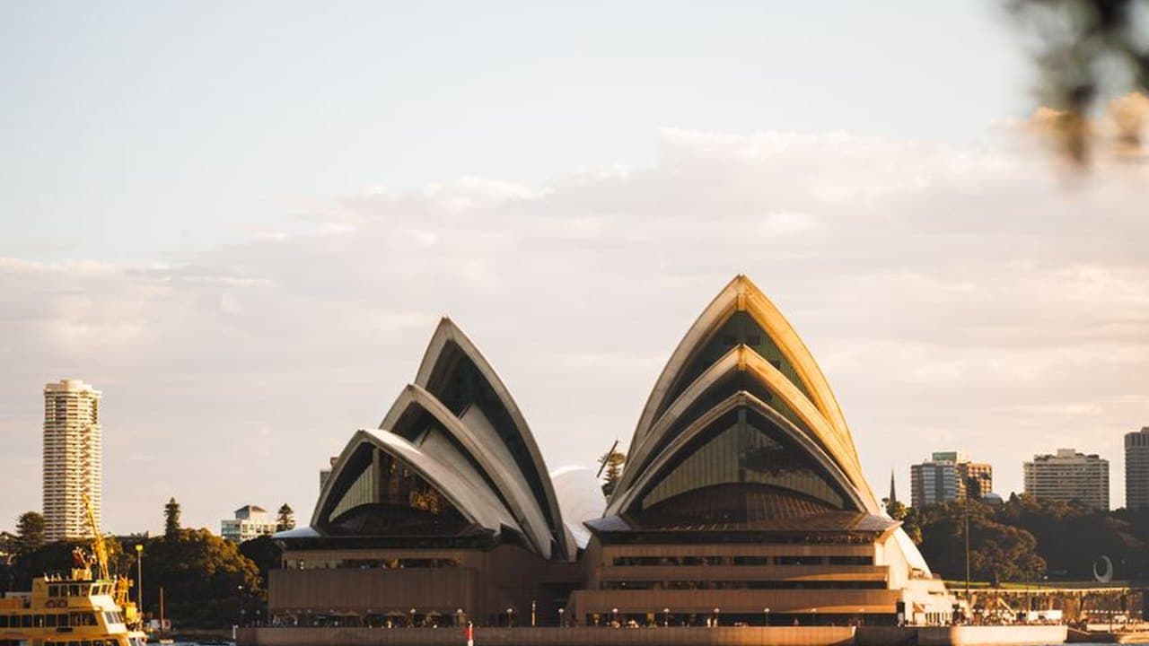 The white sail shaped shells of the Sydney Opera House against a clear sky, a building its own architect left before it was finished