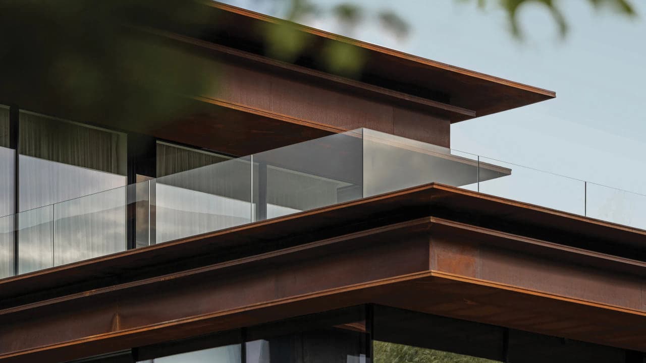 A cantilevered roofline with a slender steel fascia and a glass railing over a modern Miami facade, no people in frame
