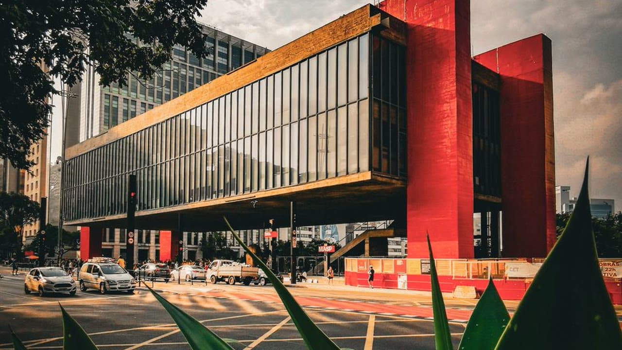 The São Paulo Museum of Art by Lina Bo Bardi, a glass volume suspended on red concrete frames above an open plaza