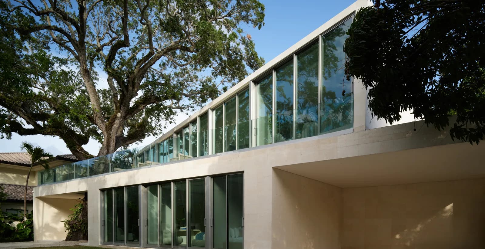 Onaway Residence exterior in Coconut Grove by LUXOM, a cantilevered travertine and glass volume showing honest materials and precise proportion