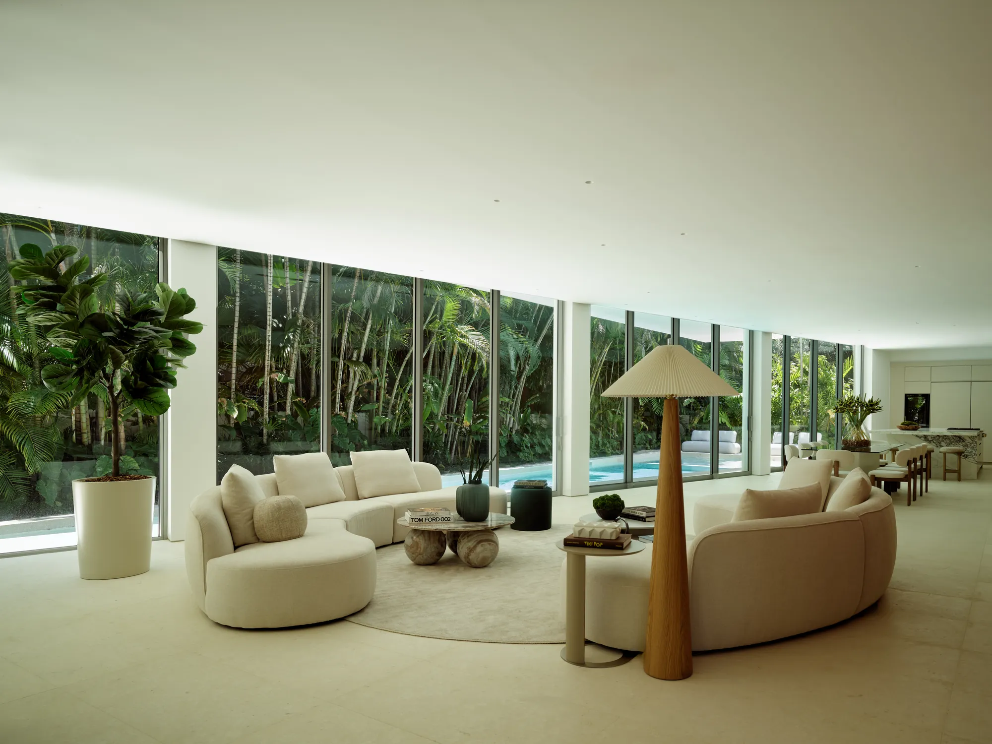 Modern living room opening to the pool through full-height glass in the Onaway residence by LUXOM, Miami