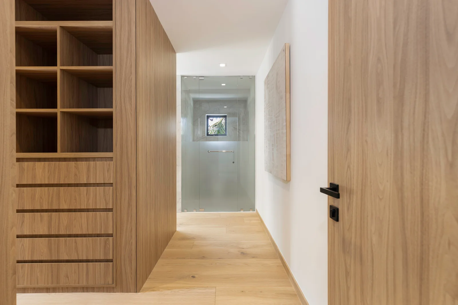 Samana residence hallway in Coconut Grove: a dark walnut closet run and door paired with light white oak flooring, two matched wood tones sharing one warm undertone