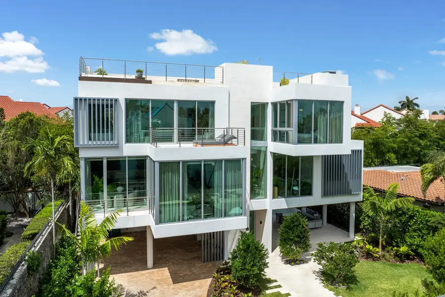 The vertically stacked exterior of Luxom's Crystal Residence in Coconut Grove, Miami, with floor to ceiling glass on every level and a roof garden crowning the primary suite floor