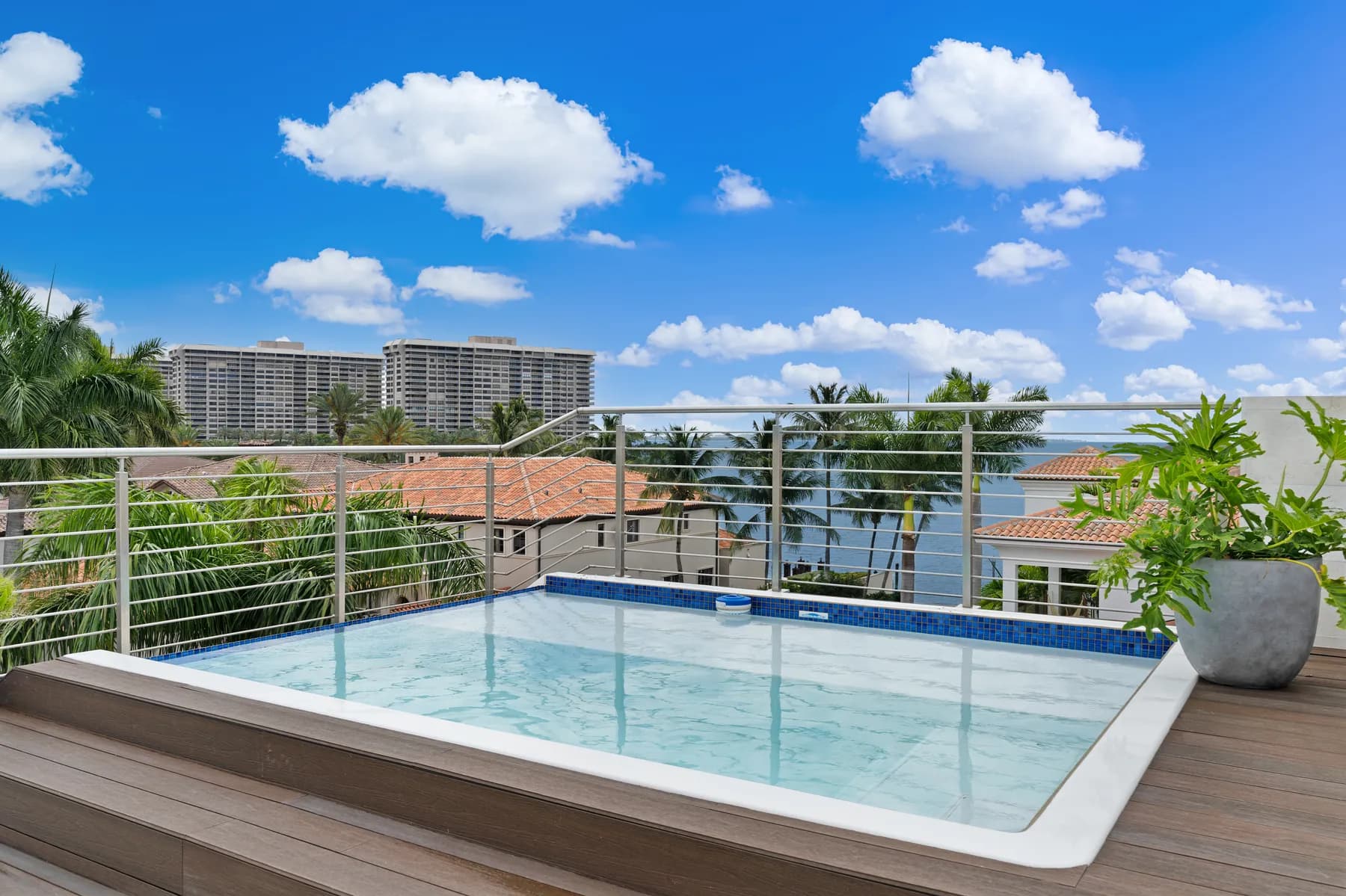 Aerial exterior view of Luxom's Crystal Residence in Coconut Grove, Miami, showing the finished rooftop plunge pool and lounge deck built on the home's uppermost level